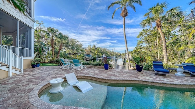 view of swimming pool with a patio area and a sunroom