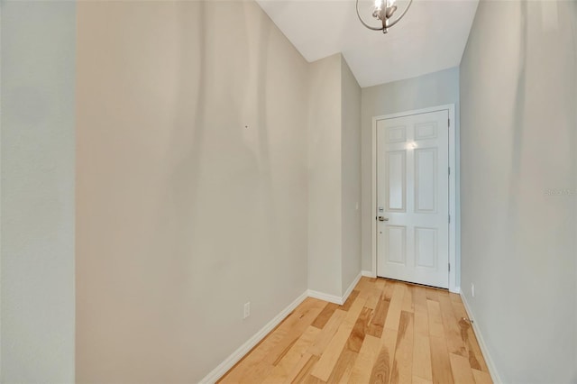 hall featuring light hardwood / wood-style floors and an inviting chandelier