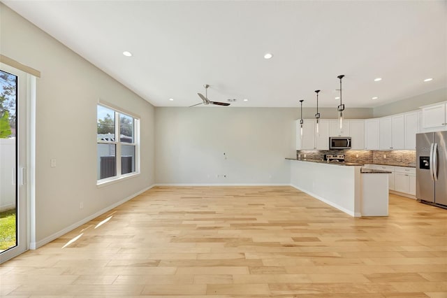 kitchen featuring kitchen peninsula, white cabinetry, light wood-type flooring, decorative light fixtures, and stainless steel appliances