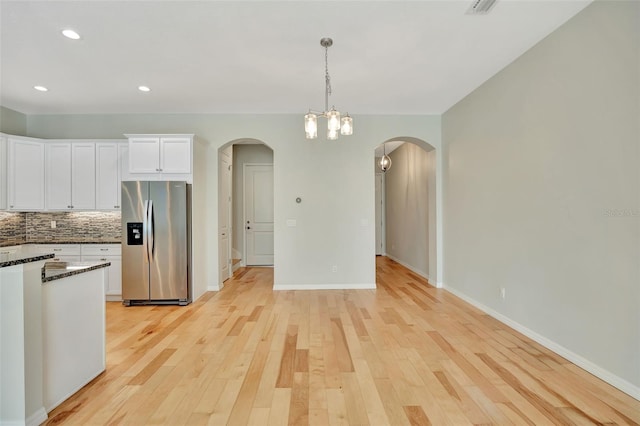 kitchen with light hardwood / wood-style flooring, stainless steel fridge with ice dispenser, a notable chandelier, decorative light fixtures, and white cabinetry