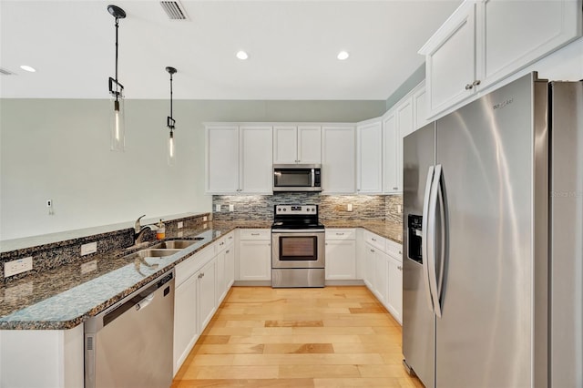 kitchen with light hardwood / wood-style flooring, stainless steel appliances, sink, pendant lighting, and white cabinets