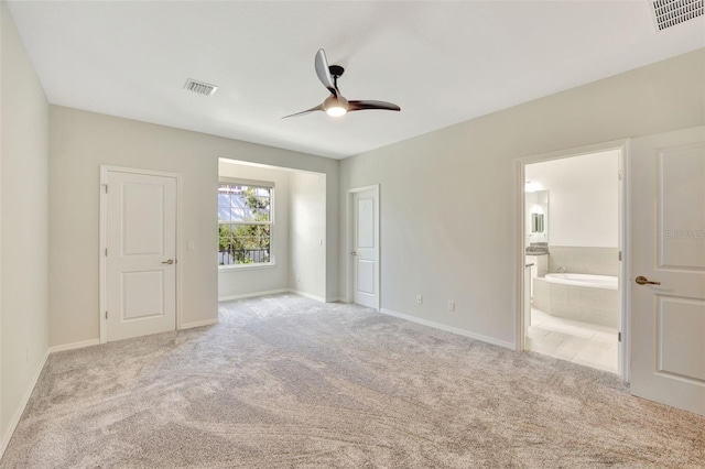 unfurnished bedroom featuring ceiling fan, light carpet, and ensuite bath