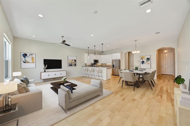 living room with light hardwood / wood-style flooring and ceiling fan with notable chandelier