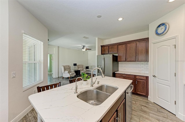 kitchen featuring ceiling fan, appliances with stainless steel finishes, an island with sink, light hardwood / wood-style flooring, and sink