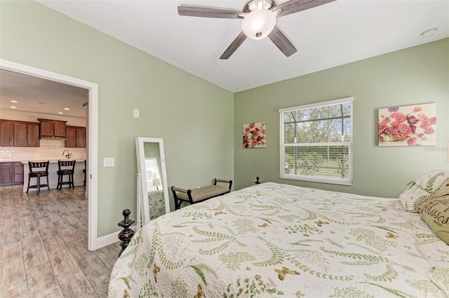 bedroom with sink, light hardwood / wood-style floors, and ceiling fan