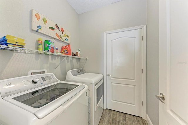 laundry room with separate washer and dryer, a textured ceiling, and light hardwood / wood-style floors