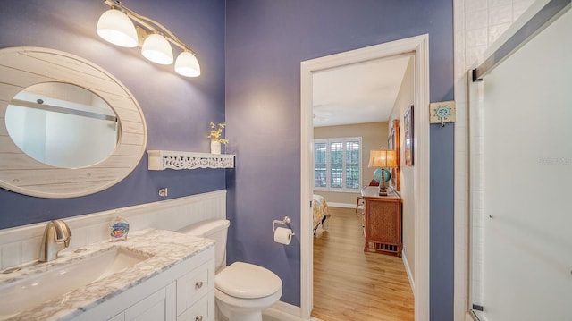 bathroom with toilet, hardwood / wood-style floors, a shower with shower door, and vanity