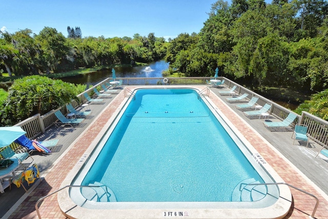 view of swimming pool featuring a patio and a water view