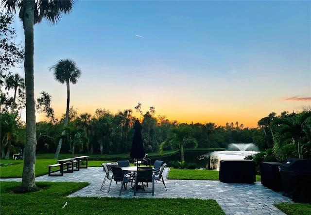 patio terrace at dusk with a yard and a water view