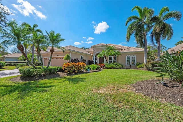 mediterranean / spanish house featuring a garage and a front lawn