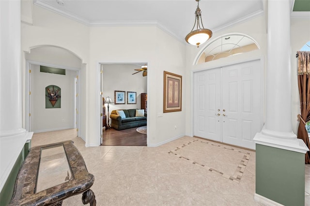 foyer with ornate columns, ceiling fan, ornamental molding, and light tile patterned flooring