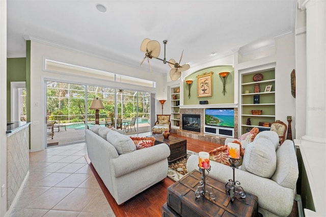 tiled living room featuring a fireplace, built in shelves, and crown molding