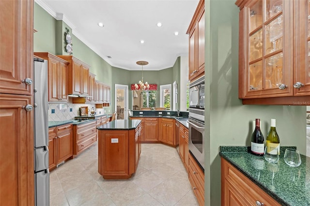 kitchen with a center island, ornamental molding, stainless steel appliances, and an inviting chandelier