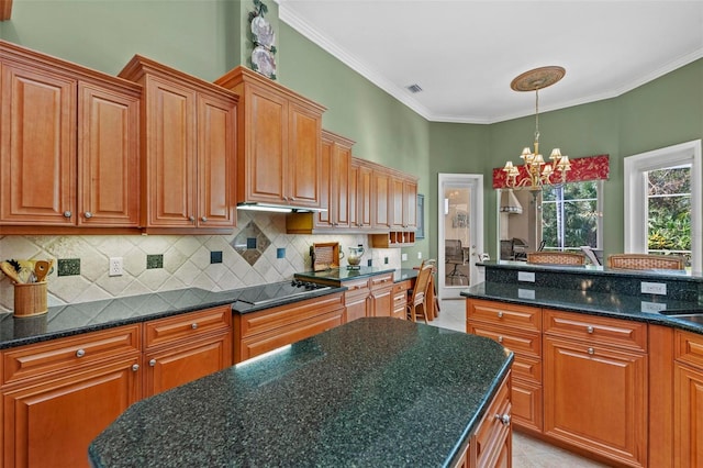 kitchen with black electric stovetop, dark stone counters, crown molding, a notable chandelier, and light tile patterned flooring