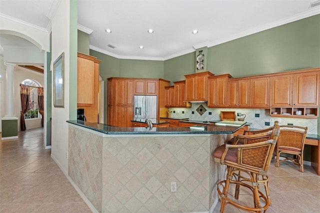 kitchen with ornate columns, stainless steel fridge with ice dispenser, kitchen peninsula, and light tile patterned flooring