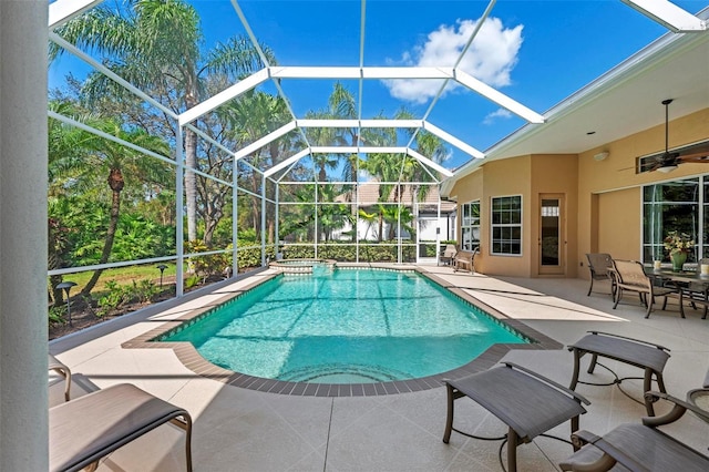 view of swimming pool featuring glass enclosure, ceiling fan, and a patio