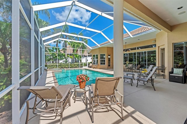 view of swimming pool with ceiling fan, a patio area, and a lanai