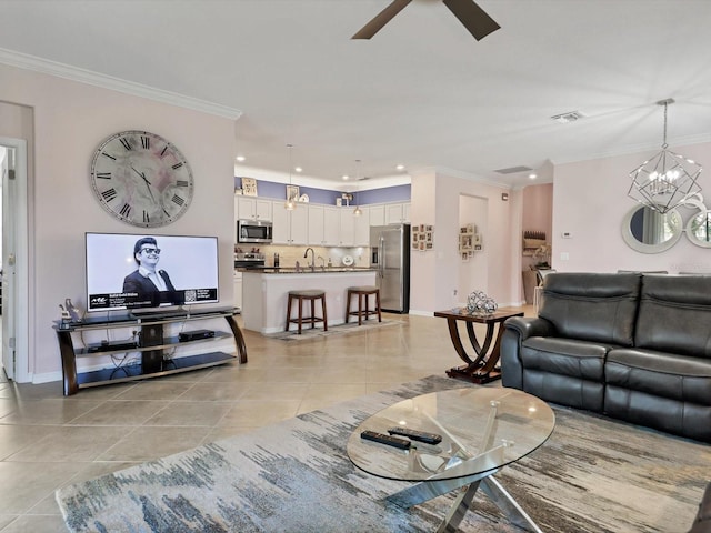 living room featuring light tile patterned floors, ornamental molding, sink, and ceiling fan with notable chandelier