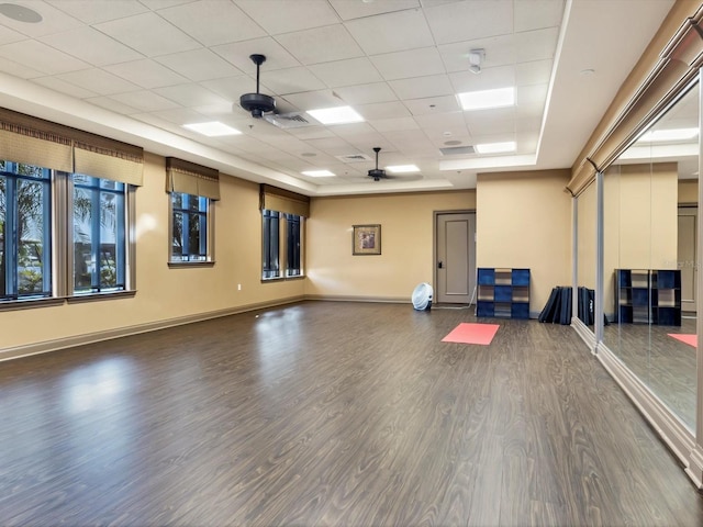 workout area with dark wood-type flooring, a paneled ceiling, and ceiling fan