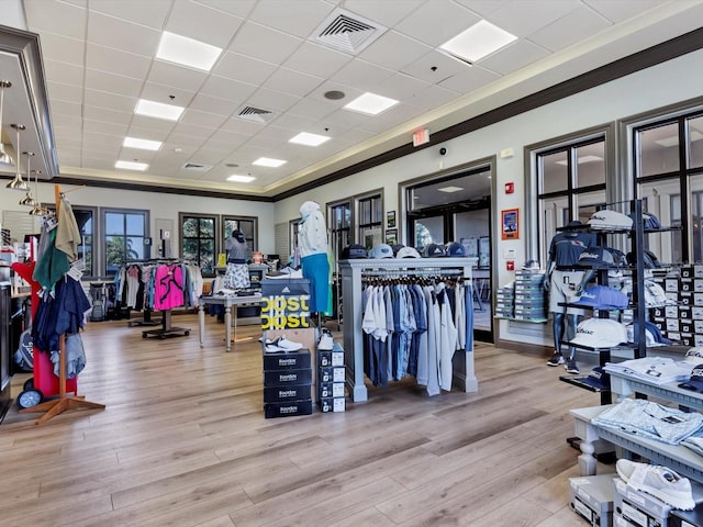 workout area featuring crown molding, a drop ceiling, and light wood-type flooring