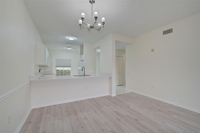 4210 Caddie Dr E Unit 102, Bradenton, FL 34203 - unfurnished dining area featuring light wood-style flooring, ceiling fan with notable chandelier, a sink, a textured ceiling, and visible vents