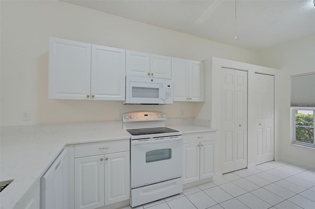 kitchen featuring white appliances, white cabinetry, and light tile patterned floors