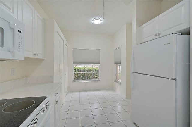 kitchen featuring white cabinetry, a textured ceiling, light tile patterned floors, and white appliances