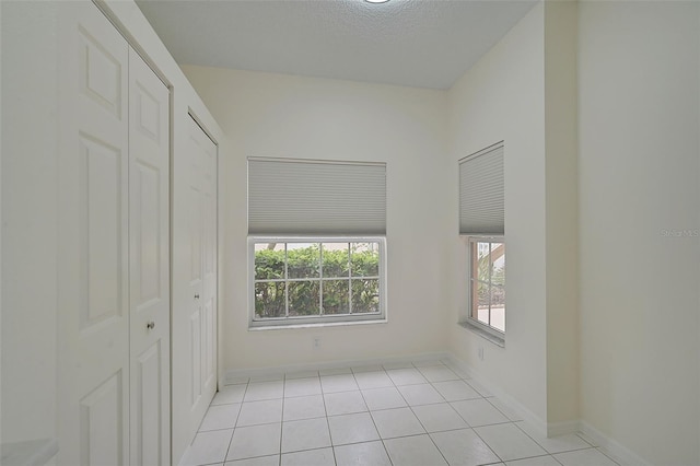 spare room featuring a textured ceiling and light tile patterned floors