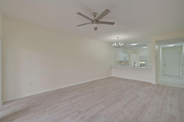 unfurnished living room featuring light hardwood / wood-style flooring and ceiling fan with notable chandelier