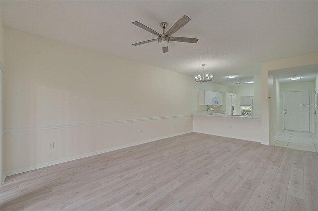 4210 Caddie Dr E Unit 102, Bradenton, FL 34203 - unfurnished living room with baseboards, light wood-style flooring, and ceiling fan with notable chandelier