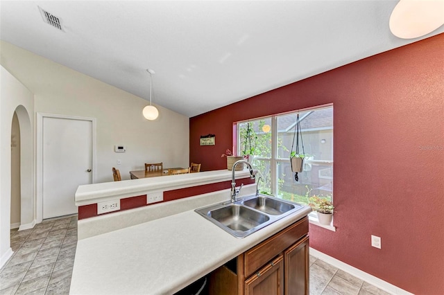 kitchen featuring sink, a center island with sink, vaulted ceiling, and pendant lighting