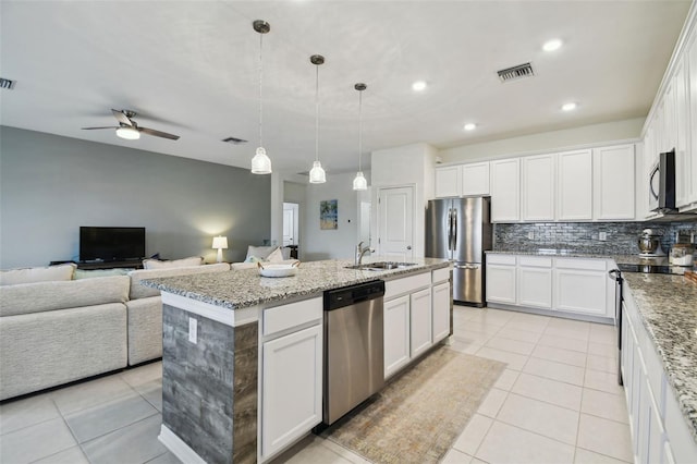 kitchen featuring stainless steel appliances, pendant lighting, white cabinets, decorative backsplash, and a center island with sink