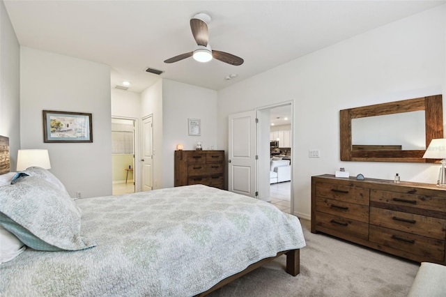 bedroom with ensuite bath, light carpet, and ceiling fan