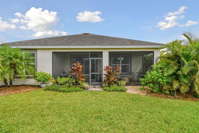 rear view of house featuring a sunroom and a lawn