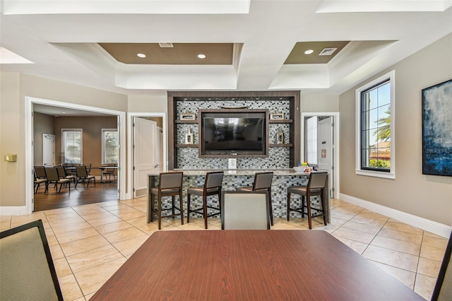 tiled dining room featuring crown molding and a tray ceiling