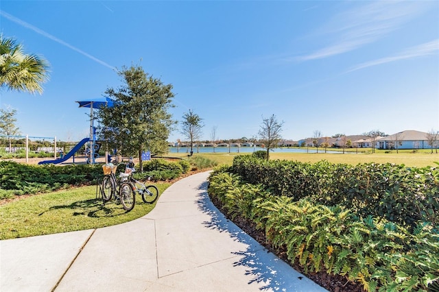 view of home's community with a playground, a yard, and a water view