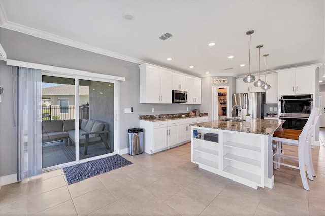 kitchen featuring white cabinetry, dark stone countertops, stainless steel appliances, and a center island with sink