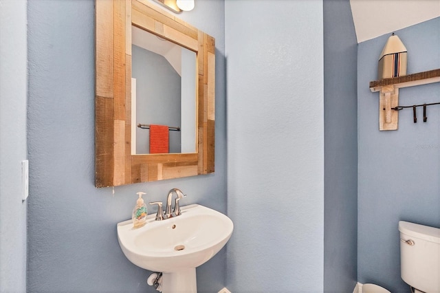 bathroom featuring toilet, lofted ceiling, and sink