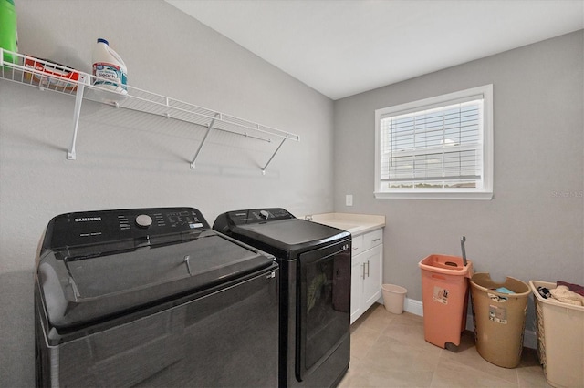 laundry area with light tile patterned flooring, washing machine and clothes dryer, and cabinets