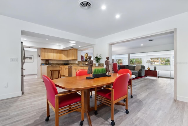 dining room featuring light wood-type flooring and a raised ceiling