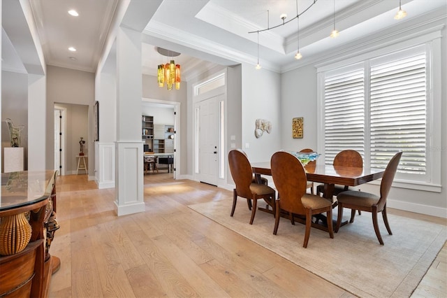 dining space with a raised ceiling, light hardwood / wood-style flooring, a wealth of natural light, and ornamental molding