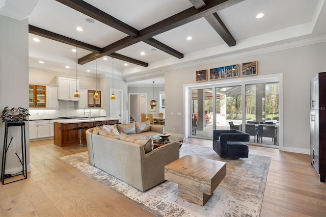 living room featuring beam ceiling, light hardwood / wood-style flooring, coffered ceiling, and sink