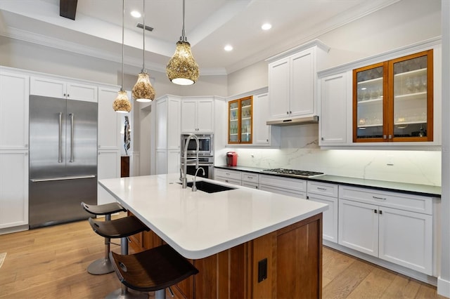 kitchen featuring white cabinets, built in appliances, decorative light fixtures, and light hardwood / wood-style flooring