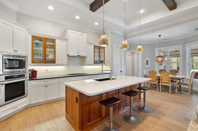 kitchen with appliances with stainless steel finishes, white cabinetry, light hardwood / wood-style flooring, and sink