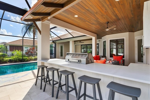 view of patio / terrace featuring an outdoor kitchen, glass enclosure, an outdoor bar, and ceiling fan