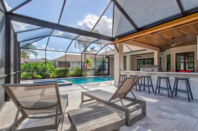 view of pool with an in ground hot tub, a lanai, ceiling fan, a bar, and a patio