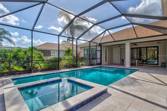 view of swimming pool with an in ground hot tub, glass enclosure, ceiling fan, and a patio area