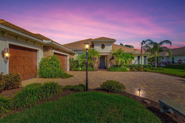 mediterranean / spanish-style house featuring a garage and a yard