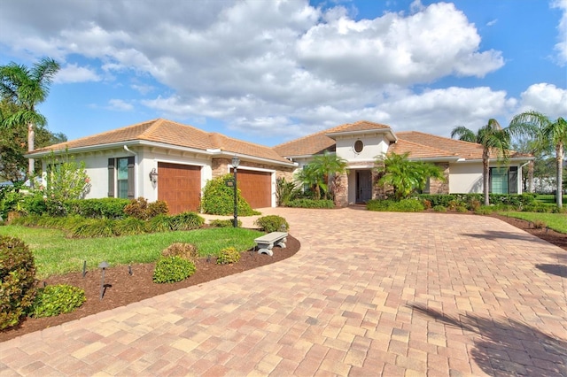 mediterranean / spanish house with an attached garage, a tile roof, decorative driveway, and stucco siding