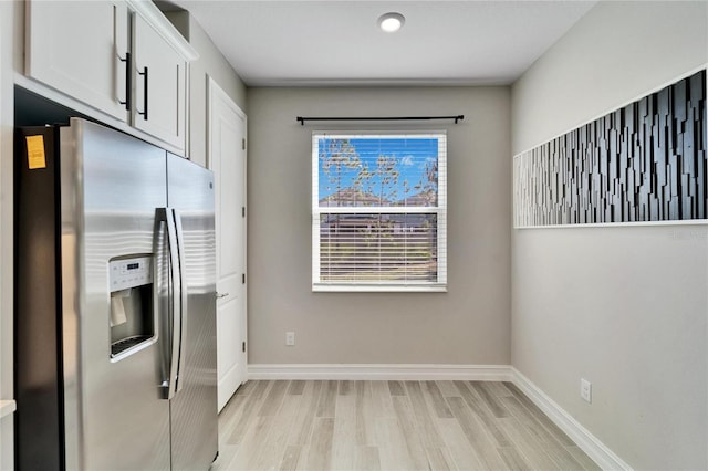 kitchen featuring white cabinets, stainless steel refrigerator with ice dispenser, and light wood-type flooring